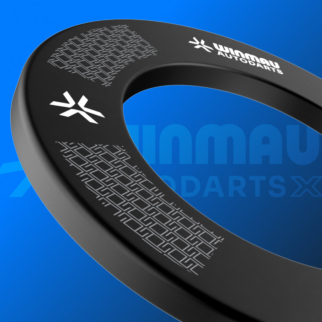 A close-up of a black Winmau Autodarts dartboard surround with white printed logos and geometric patterns, set against a blue gradient background.
